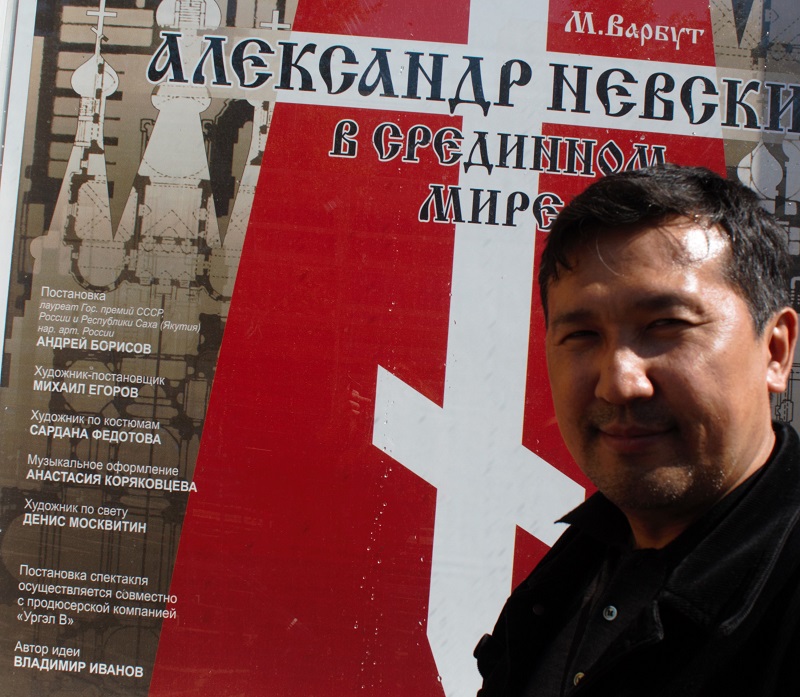 Фото В.Иванова на фоне афишы пьесы Александр Невский в Срединном мире Иркутск 1
